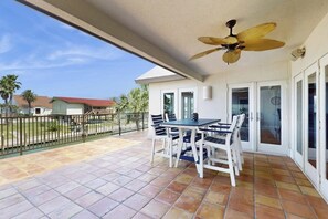 A covered patio with a table and chairs, a ceiling fan, and a view of the neighborhood. - Saltwater Solace - Under New Ownership (Rockport)