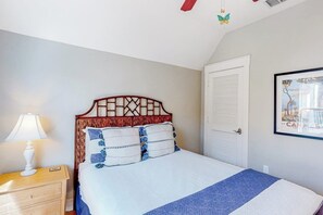 Una camera da letto con un letto, un comodino, una lampada, una porta e un quadro appeso al muro.