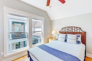 A bedroom with a large bed, a nightstand, a lamp, and a window with a view of a balcony. - Bay Dream Believer - Ocean Views & Shared Pool (Rockport)