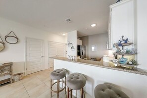 A kitchen with a central island, two bar stools, and a large mirror. - Sand Dollar Unit C3 - Bay Views & Dog-Friendly (Rockport)