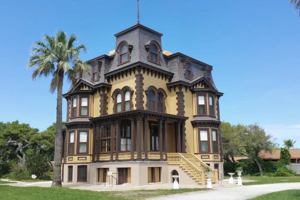 A large, historic building with multiple stories, a prominent tower, and a balcony.