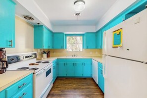 Eine Küche mit taubenblauen Schränken, einem weißen Herd und einem weißen Kühlschrank.