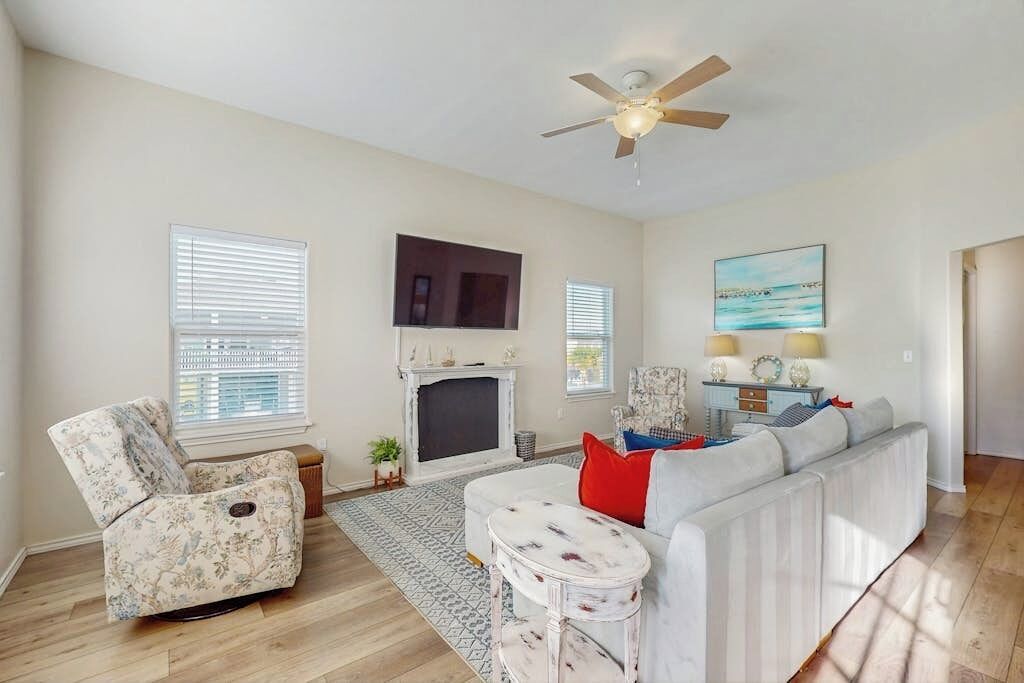 A living room with a fireplace, a sofa, a recliner, and a ceiling fan.