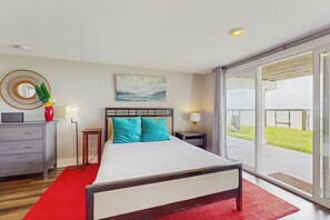 A hotel room with a bed, a desk, a chair, a lamp, a mirror, and a window with a view of the outdoors. - Salt Lake Lodge - Bayfront, Big Decks & Yard (Rockport)