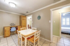 A dining area with a wooden table and chairs, a blue chair, and a decorative wall piece. - Sea Grape - Fenced Yard, Central Location (Port Aransas)