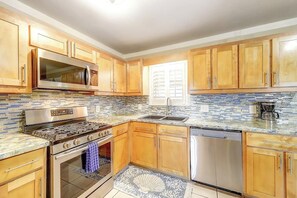 A kitchen with wooden cabinets, a stainless steel stove, a microwave, and a dishwasher. - Sea Grape - Fenced Yard, Central Location (Port Aransas)