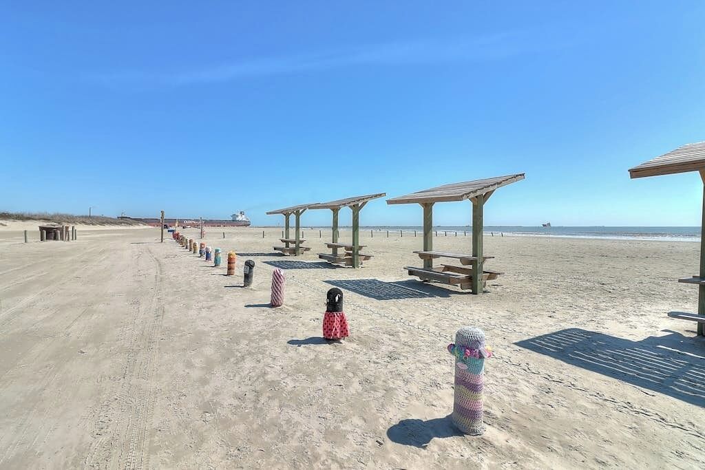 A sandy beach with wooden structures and a clear sky.