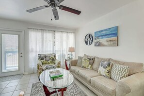 A living room with a sofa, armchair, coffee table, and a ceiling fan. - Nelray Shores at Seamist Condominiums (Port Aransas)