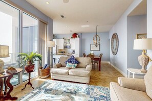 A living room with a sofa, a coffee table, and a dining area with a table and chairs. - Diamond Beach Resort Seawall Stunner (Galveston)
