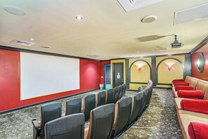 Ein Theaterraum mit Reihen von Sitzplätzen, einer Leinwand und einer Bühne.