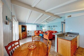 Ein geräumiger Wohnbereich mit Esstisch, Küche mit Spüle und einer gemütlichen Sitzecke mit einem roten Sofa.