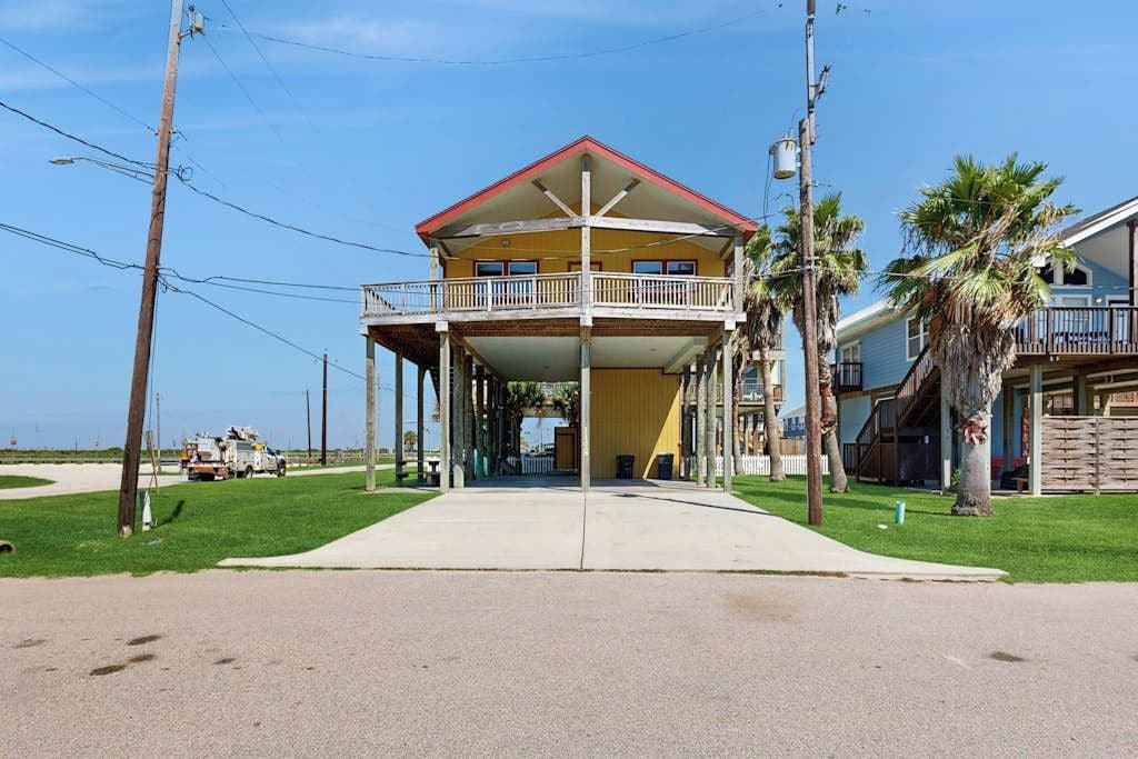 A two-story building with a balcony, a covered walkway, and a clear view of the beach.
