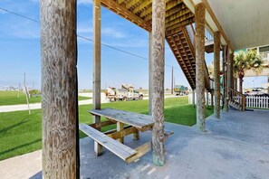 Un espacio al aire libre techado con columnas de madera y una mesa para picnic.