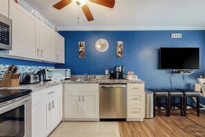 A modern kitchen with white cabinets, a stainless steel dishwasher, a microwave, and a coffee maker. - Seascape Condos #2121 (Galveston)