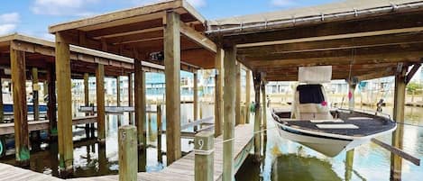 Un muelle de madera con una embarcación amarrada debajo de una zona cubierta.