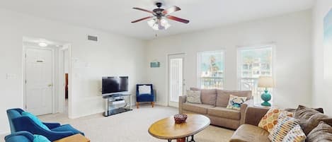 A living room with a ceiling fan, a television, and two sofas.