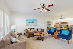 A living room with a sofa, chairs, a coffee table, and a ceiling fan. - Compass Condominiums B8 (Corpus Christi)