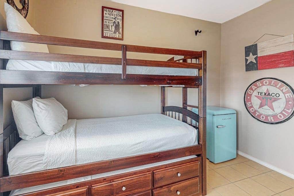 Una cama litera con estructura de madera, un cajón pequeño y un calentador fijado a la pared.