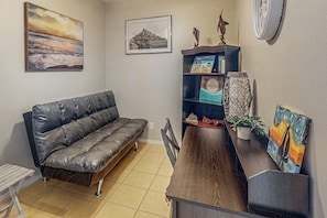 A living room with a leather sofa, a wooden coffee table, and a bookshelf with decorative items. - Star Beachside Condominiums 106 (South Padre Island)