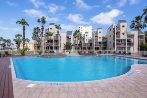 Piscina con indicador de profundidad de 1,4 metros, rodeada de palmeras y una valla blanca.