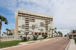 Ein mehrstöckiges Hotel mit schlichter Fassade, Balkonen und einem gepflasterten Zufahrtsweg.