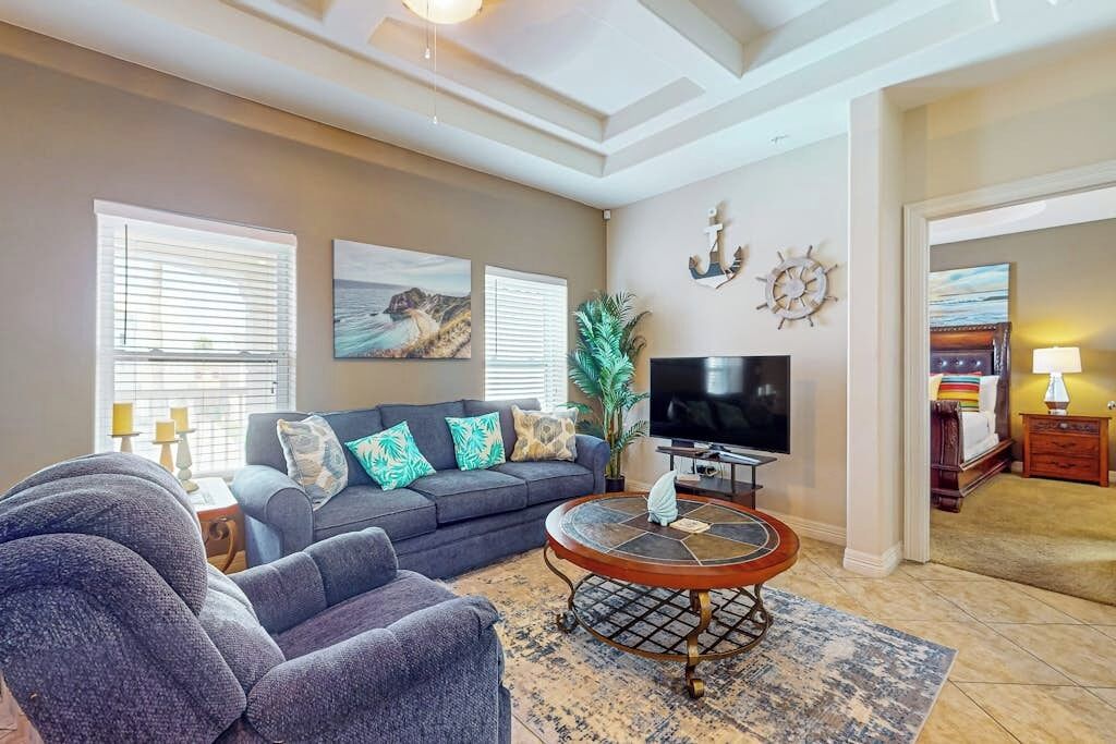 A living room with a sofa, a coffee table, a TV, and artwork on the walls.