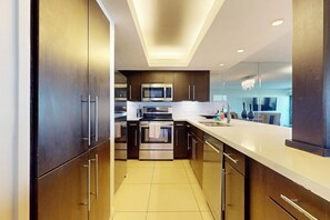 Une cuisine moderne dotée d’appareils électroménagers en acier inoxydable, de meubles en bois et d’un plan de travail blanc.