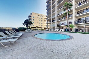 Ein Swimmingpool mit Liegestühlen und einem Gebäude im Hintergrund.