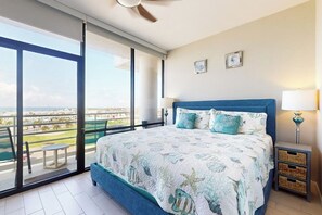 Ein Schlafzimmer mit einem großen Bett, einem Balkon und Blick sowie einem Deckenventilator.