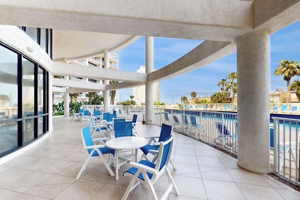 A covered outdoor area with seating and a pool view.