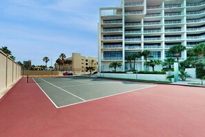 Ein Tennisplatz neben einem mehrstöckigen Gebäude mit Balkonen.