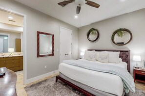 A bedroom with a bed, a ceiling fan, a mirror, and two wall-mounted wreaths. - Diamond Beach Resort - A Shore Thing (Galveston)