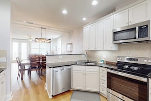 A modern kitchen with white cabinets, a stainless steel microwave, and a dishwasher. - Pointe West Resort - Sand Swept (Galveston)
