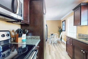 Una cocina con armarios de madera oscura, encimera de granito, estufa y microondas.