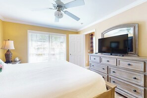 A bedroom with a bed, a dresser, a television, a ceiling fan, and a window with blinds. - Dawn Condominiums - Break of Dawn (Galveston)