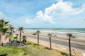 A coastal road with palm trees, a beach, and the ocean. - Dawn Condominiums - Break of Dawn (Galveston)