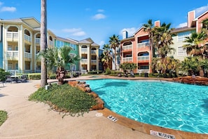 A hotel with a swimming pool, palm trees, and a clear sky. - Dawn Condominiums - Break of Dawn (Galveston)