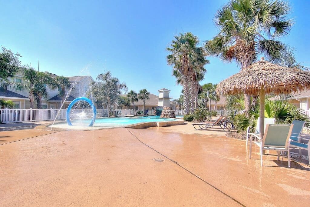 Una piscina con fontana, circondata da palme e lettini.