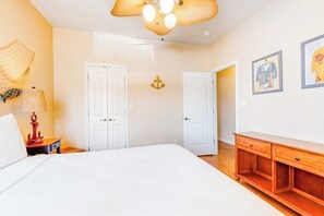 Ein Hotelzimmer mit einem Bett, zwei Türen, einer Holzkommode, einer Lampe und Wandbildern.