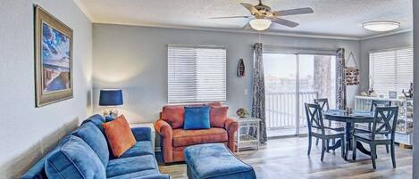 Una sala de estar con un sofá azul, un sillón naranja y una mesa de comedor con sillas.