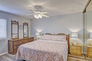Ein Schlafzimmer mit Bett, Deckenventilator, Schminktisch und Nachttisch.