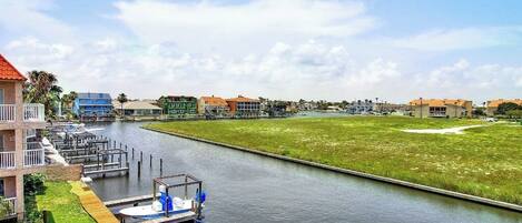 A marina with docked boats, a grassy area, and buildings in the background.