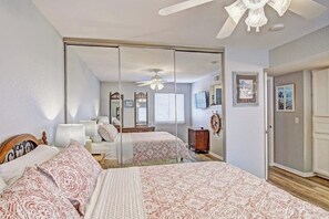 Ein Schlafzimmer mit einem großen Bett, einem Kleiderschrank, einem Deckenventilator und einem Spiegel.
