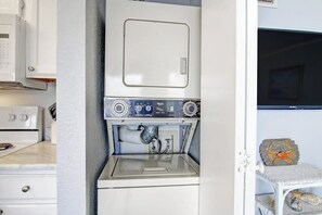 Ein kleiner Hauswirtschaftsraum mit Waschmaschine und Trockner, einem Tisch mit einer Dekoration und einem Schrank mit einer Mikrowelle.