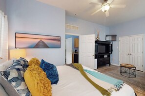 A bedroom with a bed, a ceiling fan, a television, and a painting on the wall. - Padre Island 104 - Ocean Views, Walk to the Beach (Corpus Christi)