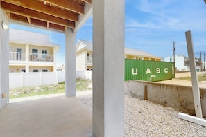 A building with a covered outdoor area, a green shipping container labeled 'UASC,' and a white fence in the background. - Padre Island 104 - Ocean Views, Walk to the Beach (Corpus Christi)