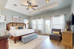 A bedroom with a bed, a chair, a desk, a ceiling fan, and a TV. - Padre Island 104 - Ocean Views, Walk to the Beach (Corpus Christi)