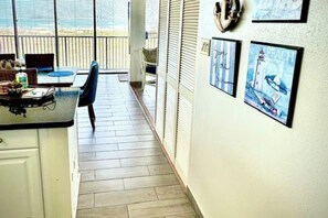 A kitchen with a counter, a chair, and a dining table. There are framed pictures on the wall. - The Beach Condo #204 (South Padre Island)