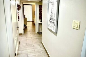 Un couloir étroit, doté d’un plancher en bois, mène à une pièce avec une fenêtre.