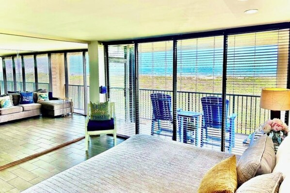 A spacious balcony with a sofa, chairs, and a table. - The Beach Condo #204 (South Padre Island)
